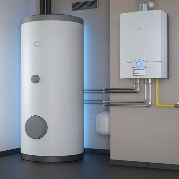 Weißer zylindrischer Warmwasserspeicher neben einem an der Wand montierten tanklosen Warmwasserbereiter, verbunden durch freiliegende Metallrohre, in einem sauberen modernen Hauswirtschaftsraum mit grauen Wänden und schwarzem Boden.